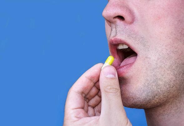 Viên uống mới giúp giảm cholesterol LDL: Bước tiến trong phòng ngừa nhồi máu cơ tim và đột quỵ- Ảnh 1. Chàng trai trẻ đặt viên thuốc màu vàng vào miệng, hình ảnh được tách biệt trên nền xanh. Chàng trai nuốt thuốc.